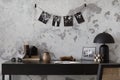 Concrete interior of home office with desk, image, lamp and office accessories. Grey concrete wall. Home decor. Template