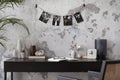 Concrete interior of home office with black desk, image, lamp and office accessories. Grey concrete wall. Home decor. Template