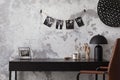 Concrete interior of home office with desk, image, lamp and office accessories. Grey concrete wall. Home decor. Template