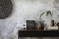 Concrete interior of home office with desk, image, lamp and office accessories. Grey concrete wall. Home decor. Template