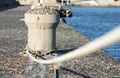 Concrete mooring bollard with a rope at a dock. Royalty Free Stock Photo