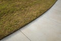 A concrete pedestrian footpath with a perfect lawn edge. Concept of garden landscaping, lawn edging, and grass maintenance. Royalty Free Stock Photo