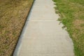A concrete pedestrian footpath with a perfect lawn edge on one side and overgrown grass on the other. Concept of garden landscapin Royalty Free Stock Photo