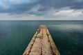 Concrete pier in the middle of the sea against the background of a gray cloudy sky Royalty Free Stock Photo