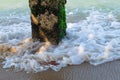 Concrete pillar with green moss and waves in the sea Royalty Free Stock Photo