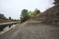 Concrete ramp with trees arching on it by the side of a diversionary channel on a cloudy day in the italian countryside