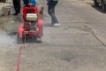 Concrete Road Cutters with worker. Worker using diamond saw blade machine cutting concrete road at construction site. Concrete cut Royalty Free Stock Photo