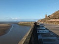 Concrete stairs on seawall in the cliffs area blackpool with the beach at low tide in sunlight with the old boat pool and tower in Royalty Free Stock Photo