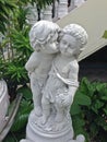 A concrete statue of a young boy kissing a girl on the cheek. Royalty Free Stock Photo