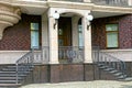 Concrete steps and iron forged handrails on the facade of a house with columns and lanterns on the street