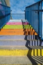 Concrete steps painted bright rainbow colours with a blue railing and a strong shadow pattern Royalty Free Stock Photo