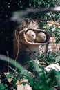 The concrete stone head of a Bender robot from the Futurama cartoon stands among green foliage Royalty Free Stock Photo
