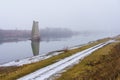 Concrete support of the blown up bridge on the river in damp foggy weather. Consequences of the war. Background