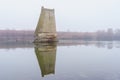 Concrete support of the blown up bridge on the river in damp foggy weather. Consequences of the war. Background