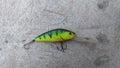 On the concrete surface lies a spinning lure - a plastic wobbler painted to look like a bass, with two triple hooks and pike teeth Royalty Free Stock Photo