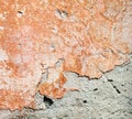 Concrete surface with the remains of orange paint and whitewash and partly fallen plaster