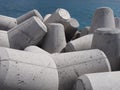 Concrete tetrapods used to prevent coastal erosion in interlocking heaps in front of a bright blue sea