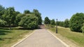 Concrete tile stairs lead from a city park to a city block. Nearby are mowed grassy lawns, various deciduous trees, metal lamppost Royalty Free Stock Photo