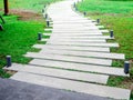 Concrete walkway with modern design pattern with garden lights on green grass Royalty Free Stock Photo