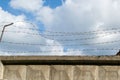 Concrete wall, against the background of blue sky barbed wire, the concept of prison, rescue, refugee, loneliness, space for text Royalty Free Stock Photo