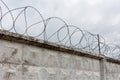 Concrete wall with barbed wire and gray sky
