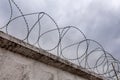 Concrete wall with barbed wire and gray sky