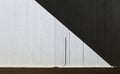 Concrete wall divided obliquely in black and white colors. Tight sidewalk and asphalt road in front.