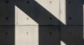 Concrete wall with evenly spaced circular indentations casts sharp, geometric shadows. The surface Royalty Free Stock Photo