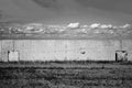 Concrete wall on field and flying swallow in sky. Black and whit