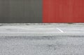 Concrete wall painted half red and half gray with an asphalt road in front. Background for copy space Royalty Free Stock Photo