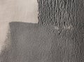 Concrete wall partially painted in gray with a paint roller. Paint texture in side sunlight Royalty Free Stock Photo