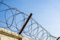 Concrete wall with razor barbed tape wire on blue sky background on a Sunny day Royalty Free Stock Photo