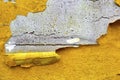 Concrete wall with yellow, orange peeling paint old cracked damaged rough bright background texture Royalty Free Stock Photo