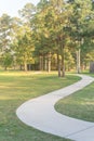 Concrete winding concrete pathway and tall trees at green suburban park in Houston, Texas, USA Royalty Free Stock Photo