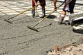 Concrete workers leveling the wet mud on a newly poured driveway. Royalty Free Stock Photo