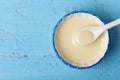 Condensed milk or evaporated milk in bowl on blue table top view. Royalty Free Stock Photo