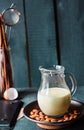 Condensed milk in a jug glass, dark almonds on a plate