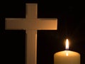 Burning candle under Jesus cross in a cemetery against black background.