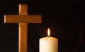 Burning candle under wooden cross in a cemetery against black background. Royalty Free Stock Photo