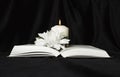 Condolence card. A white memorial candle with white flowers and an open book. The funeral, the sadness. Royalty Free Stock Photo