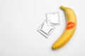 Condoms and banana with kiss mark on white background, top view. Safe sex