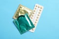 Condoms and birth control pills on blue background, flat lay. Safe sex concept