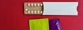 Condoms and birth control pills on red background, flat lay