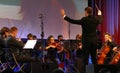 Conductor directing symphony orchestra with performers on background during the opening ceremony of Business Bled Strategic Forum