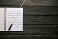 Conductor`s baton and sheet music book on black wooden table, top view. Space for text Royalty Free Stock Photo