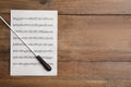 Conductor`s baton and sheet music on wooden table, top view. Space for text Royalty Free Stock Photo