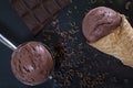 A cone with chocolate ice cream, a ball of ice cream in a spoon, a chocolate bar on a black surface Royalty Free Stock Photo