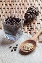 Cone, pine nuts in the glass and shelled nuts in the wooden spon on the braided surface.