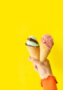 A cone of refreshing ice cream in a waffle cup against a yellow wall. The concept of vacation, vacation at sea. A woman holds ice Royalty Free Stock Photo