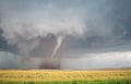 A cone tornado spins over the open landscape of the Great Plains.